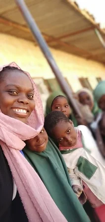 a lady smilling with children in the school yard