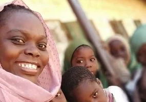 a lady smilling with children in the school yard