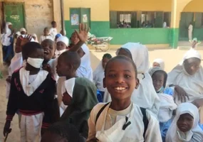 children in the school yard waving at the camera