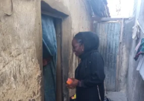 a lady in black waiting for a child to come out of the of a house